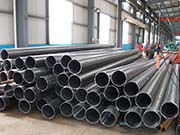 What causes the bending during the production of straight seam steel pipes